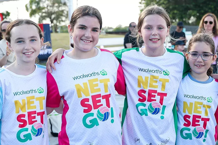 Four children smiling, standing side-by-side wearing matching 