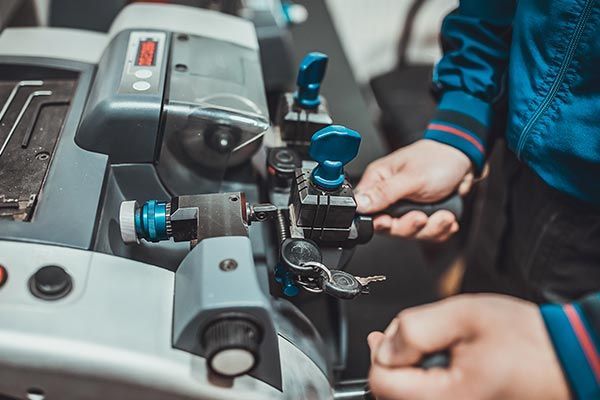 A person is cutting a key with a machine. A person is cutting a key with a machine.