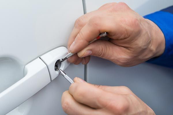 A person is using a screwdriver to fix a car door lock. A person is using a screwdriver to fix a car door lock.