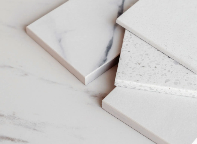 A man is talking on a cell phone while using a laptop computer in a warehouse.