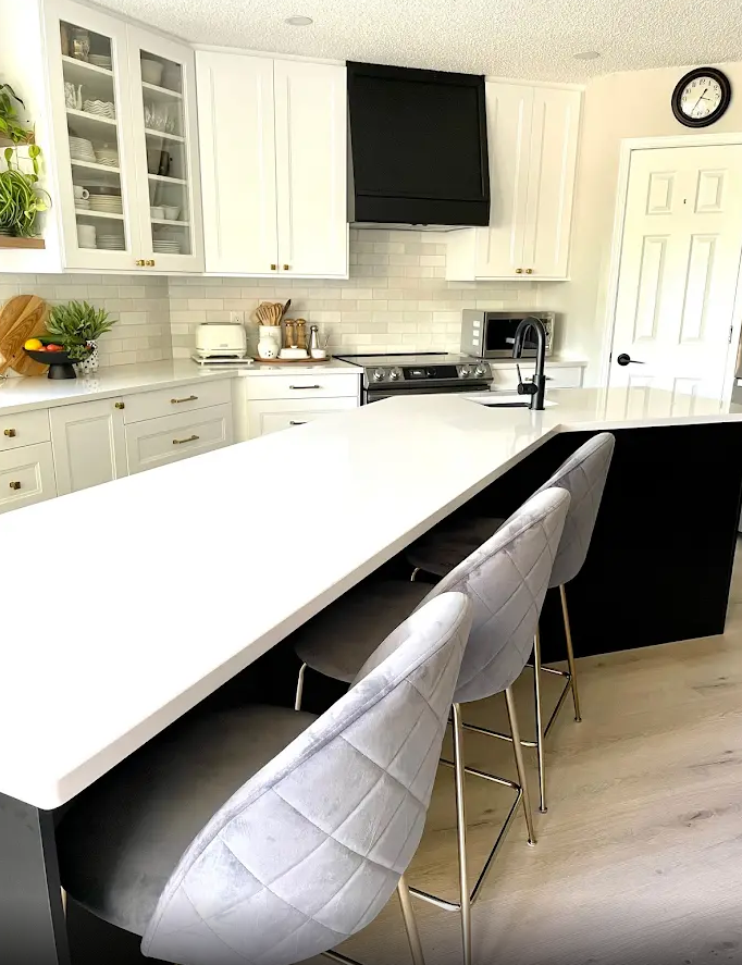 A kitchen with white cabinets and a black island