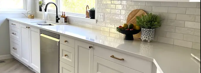 A kitchen with white cabinets , a sink , and a dishwasher.