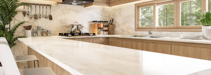 A kitchen with white counter tops and wooden cabinets and a large window.