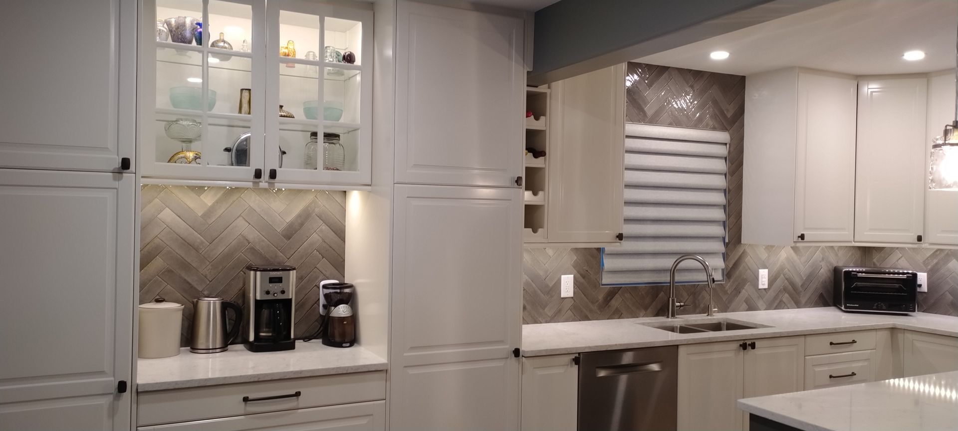 A kitchen with white cabinets , a sink , and a window.