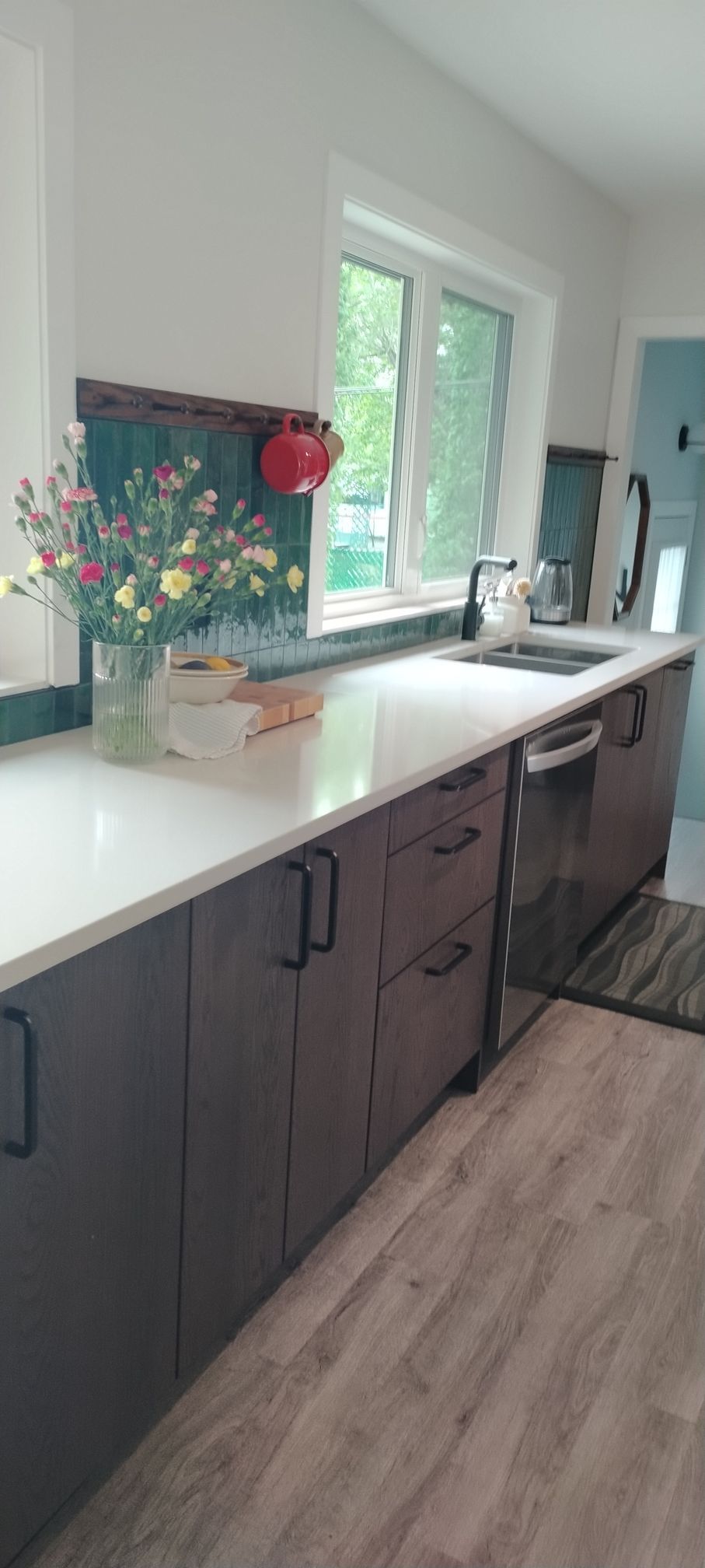 There is a vase of flowers on the counter in the kitchen.