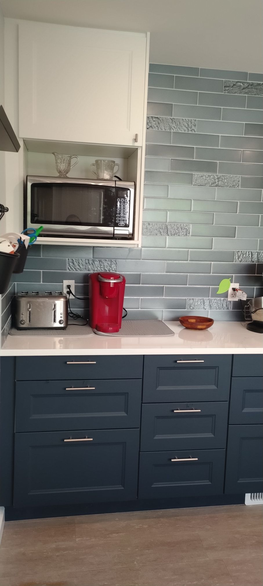 A kitchen with blue cabinets , a microwave , a toaster , and a coffee maker.