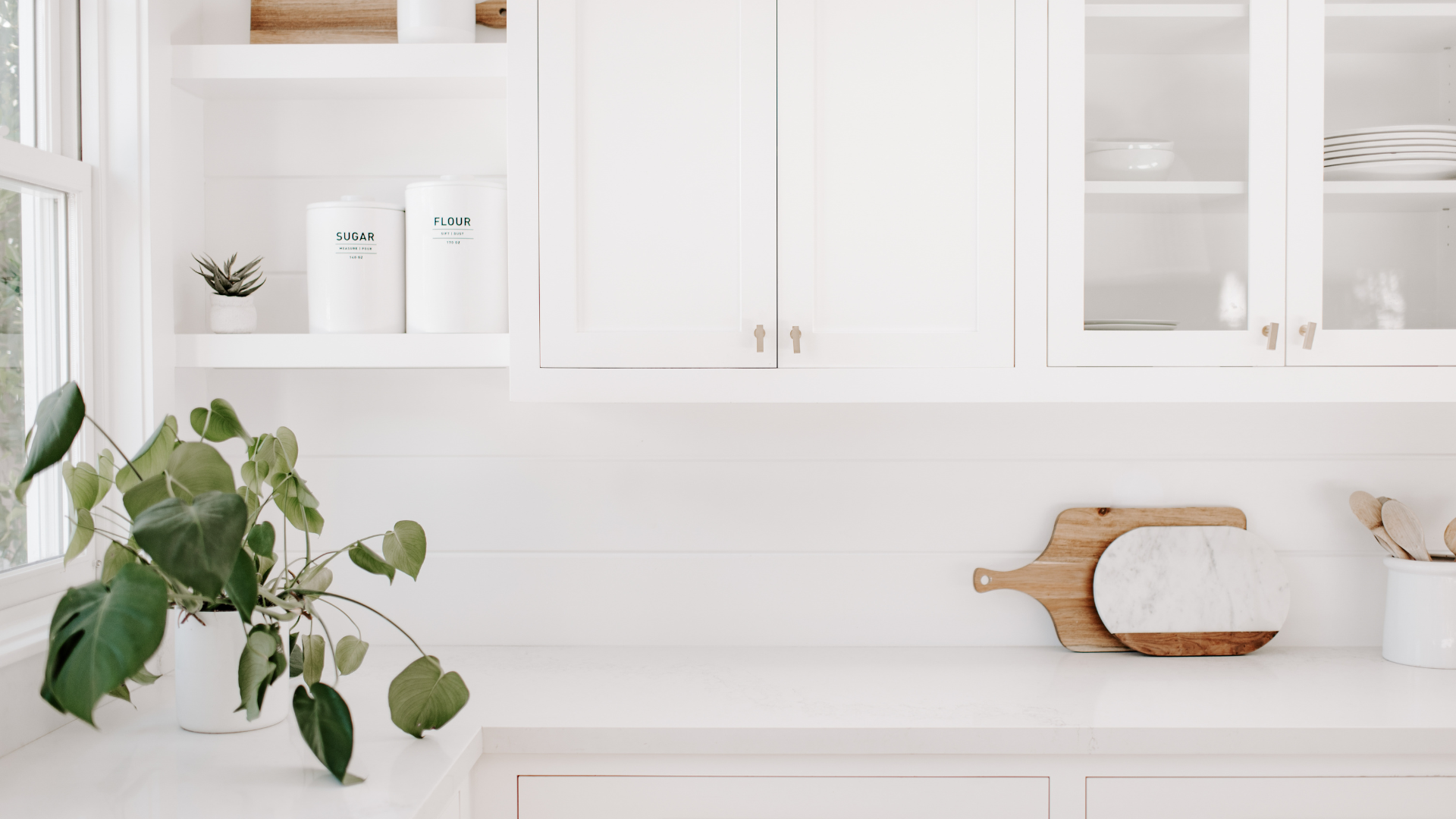 A kitchen with white cabinets and a wooden cutting board on the counter.