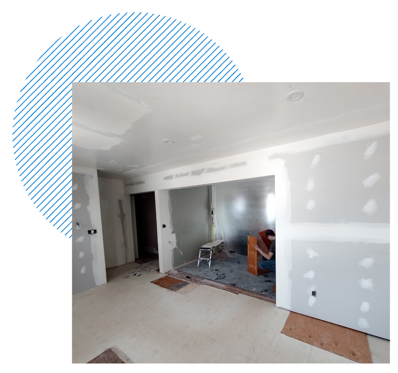 A man is working on a wall in a room that is being remodeled.