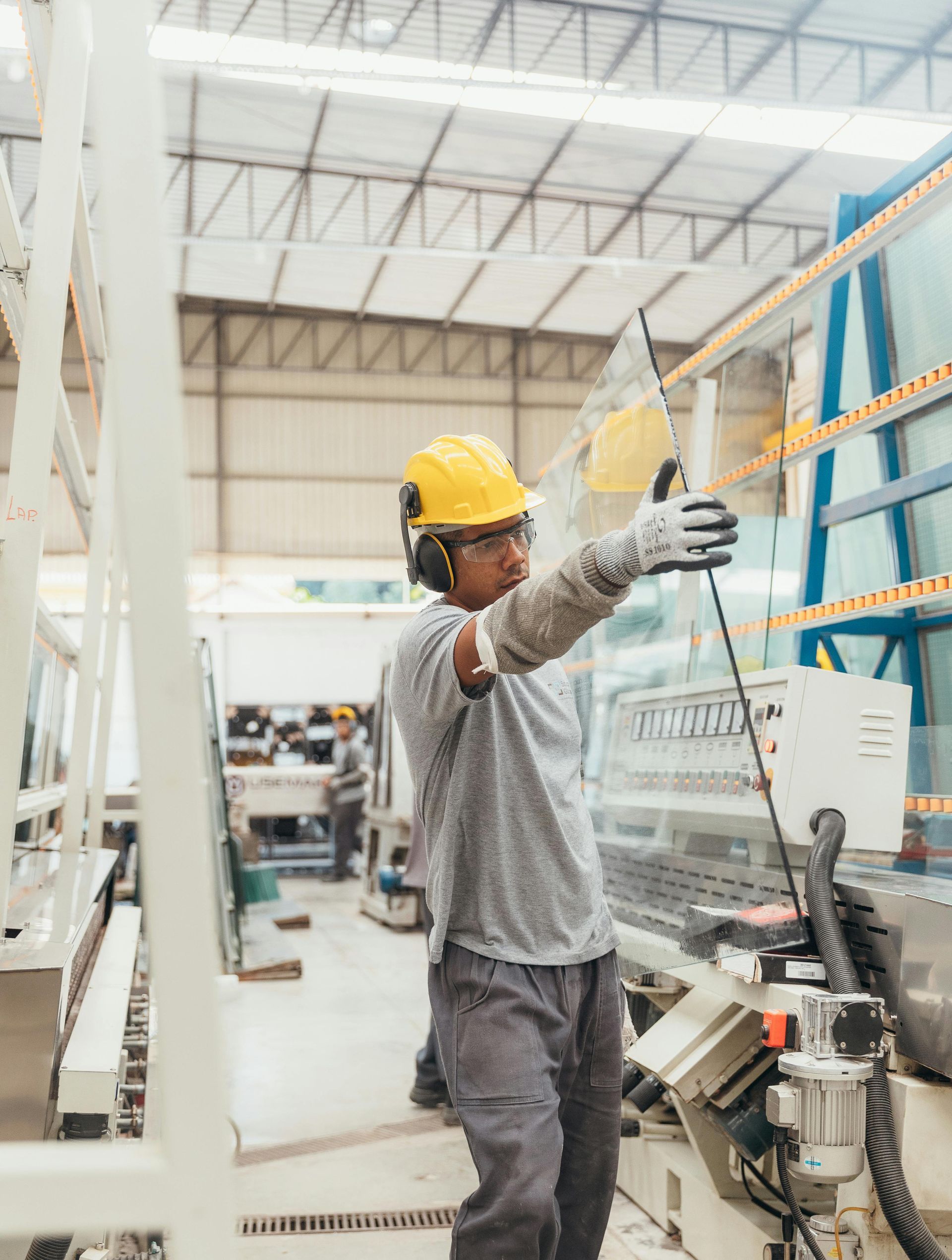 Worker in yellow hard hat inspecting equipment in a factory aisle