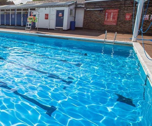 A large swimming pool with a lifeguard tower in the background