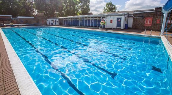 A group of people are swimming in a large swimming pool.