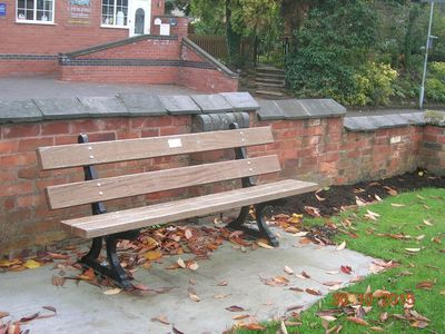 A wooden bench sits in front of a brick wall