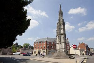 A large stone tower is in the middle of a city square.