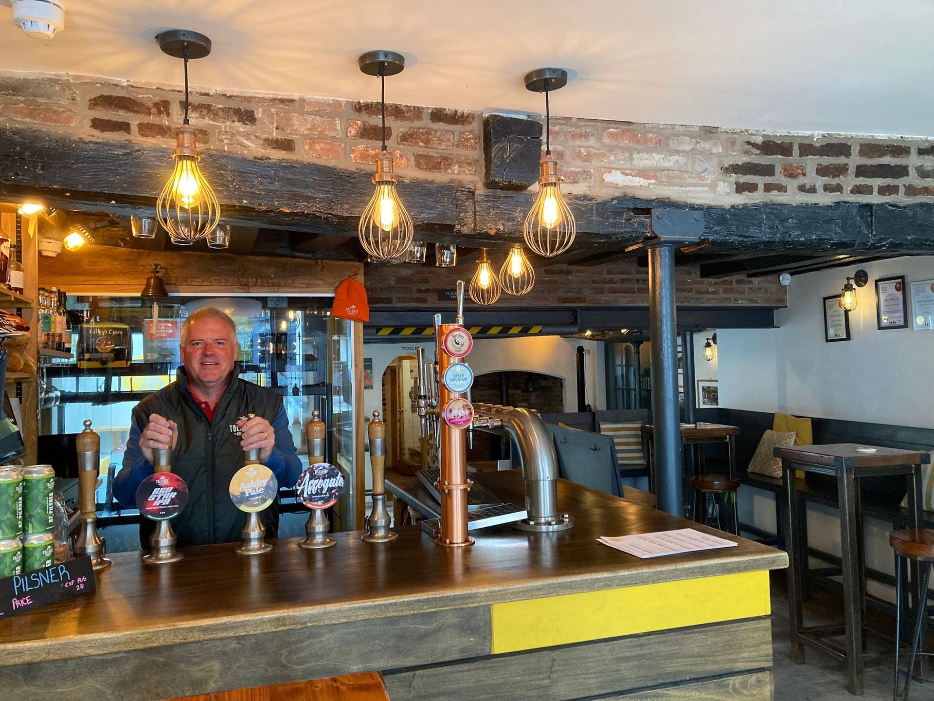 A man is standing behind a bar in a restaurant.