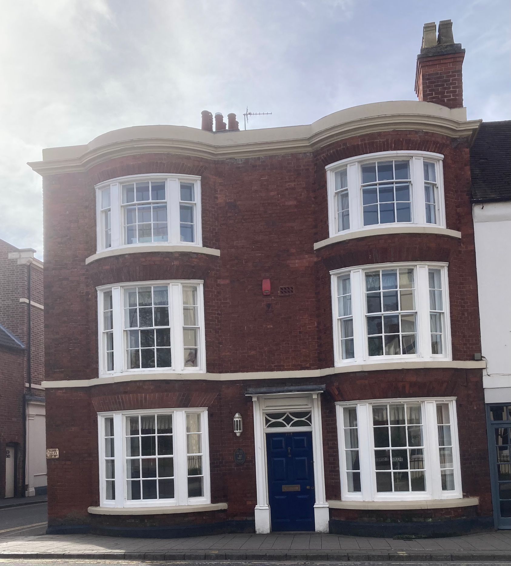 A red brick building with white windows and a blue door