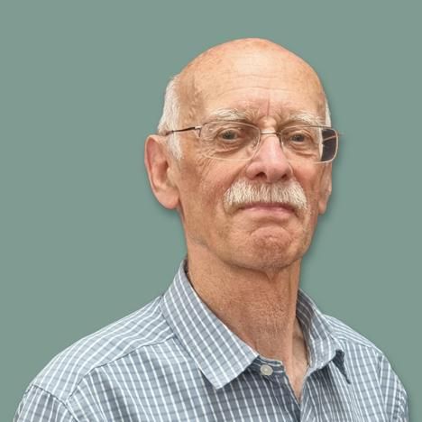Ken Ward with glasses and a mustache is wearing a plaid shirt.