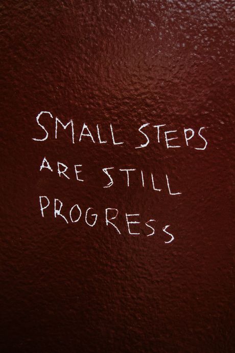 Handwritten white text on a dark background: “Small steps are still progress.”