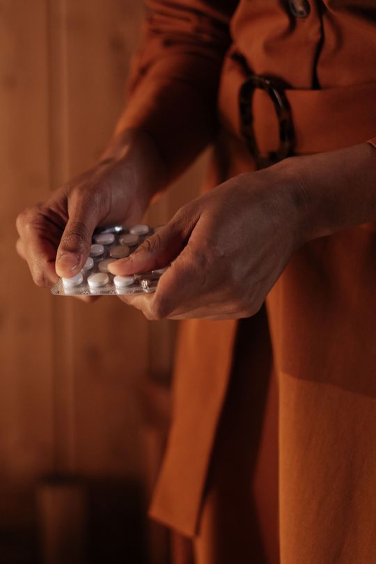 Spilled prescription pill bottles with scattered white tablets on a dark surface
