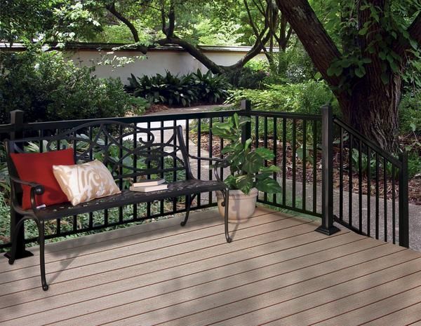 A wooden deck with a black railing and a bench with pillows on it in Columbus