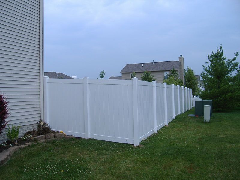 A white fence is in the backyard of a house in Columbus