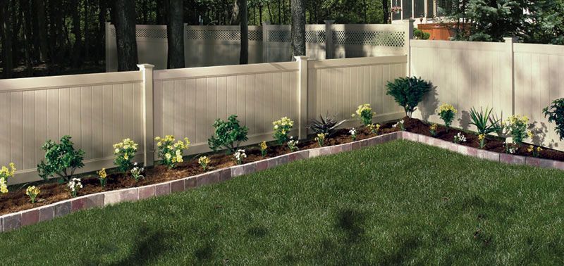 A white fence surrounds a lush green yard with flowers and shrubs in Columbus