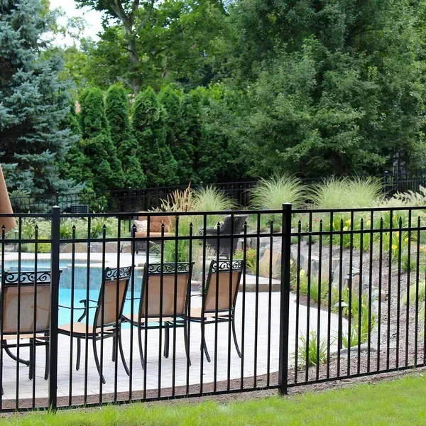 A black metal aluminium fence surrounds a swimming pool with chairs and umbrellas in Columbus
