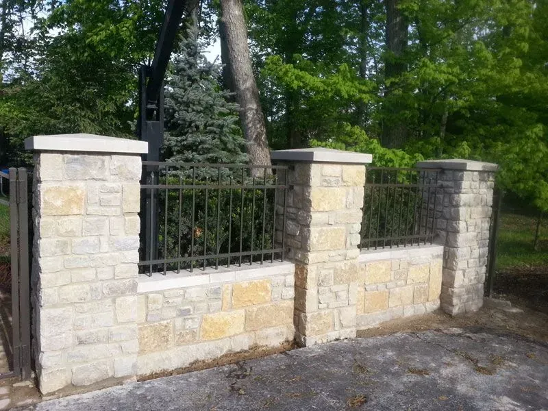 A stone wall with a wrought aluminum fence around it in Galena