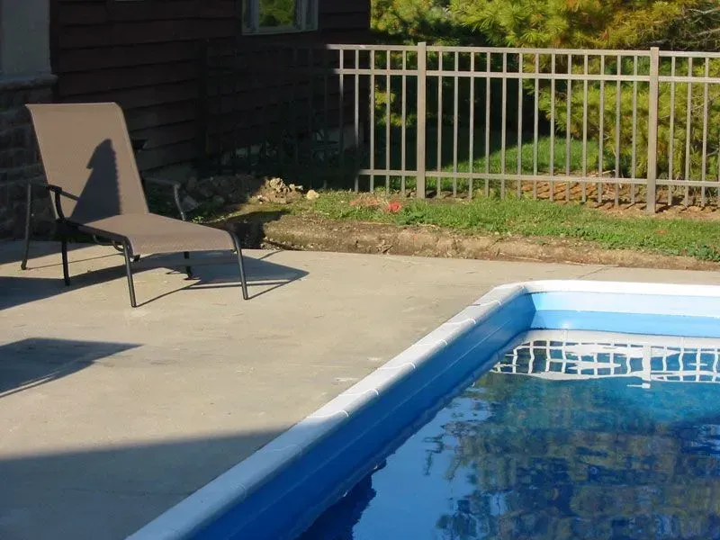A swimming pool is surrounded by a aluminum fence and chairs in Columbus