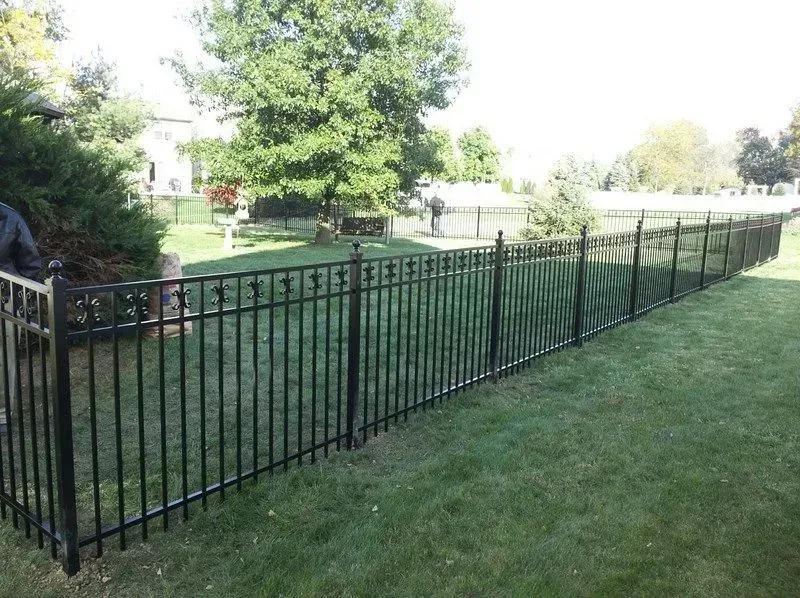 A black metal fence surrounds a lush green yard in Upper Arlington