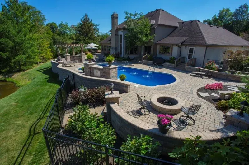An aerial view of a large house with a large swimming pool and a fire pit in Columbus
