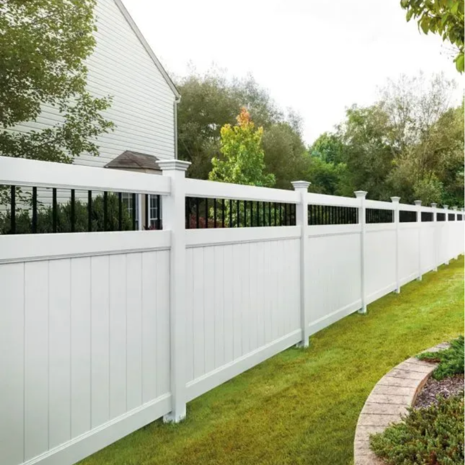 A white vinyl privacy fence with black vertical slats at the top, standing along a lawn next to a house in Columbus