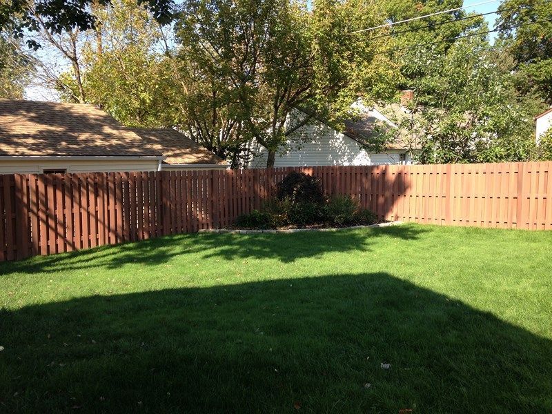 A backyard with a wooden fence and a lush green lawn in Columbus