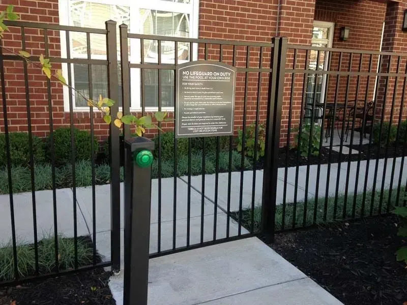 A black aluminum fence with a sign on it in front of a brick building in Columbus