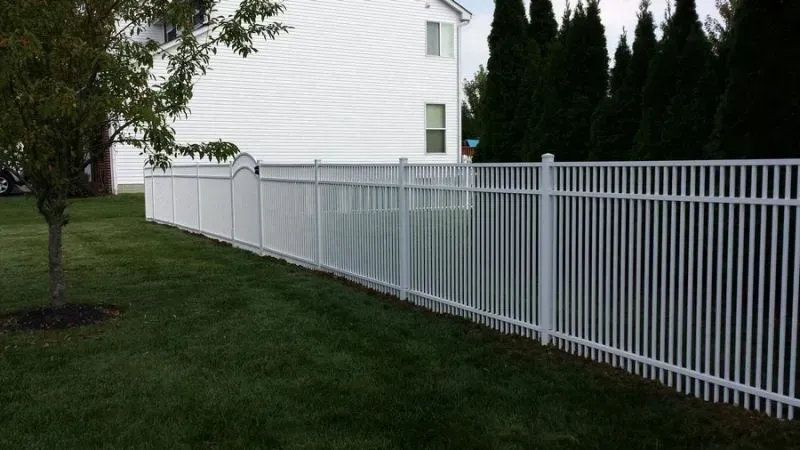 A white aluminum fence surrounds a lush green yard in front of a white house in Columbus