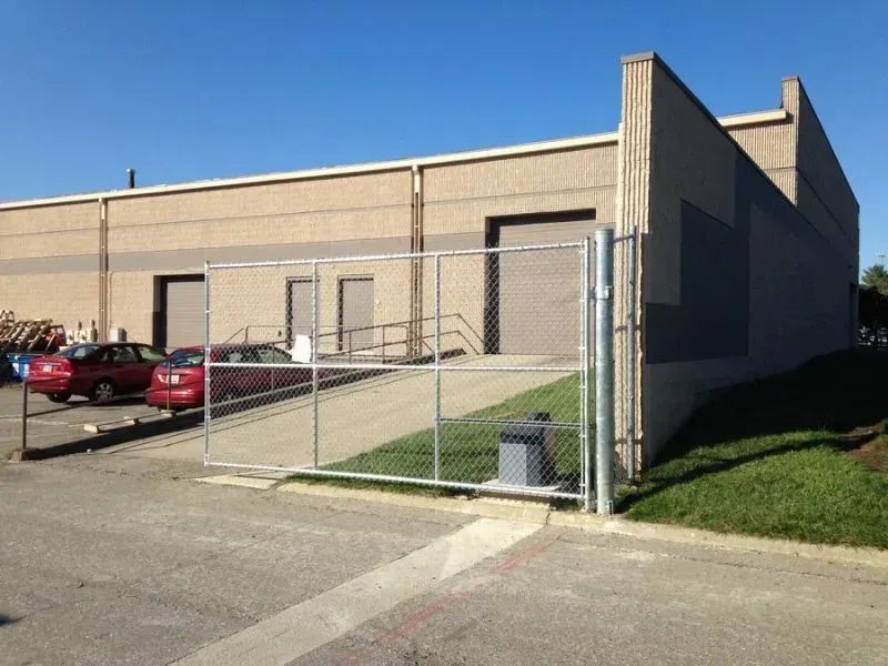 A chain link fence surrounds a building with cars parked in front of it Columbus