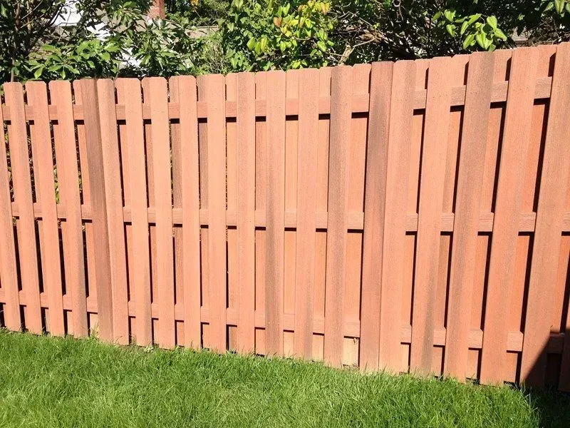 A composite fence is sitting on top of a lush green lawn in Columbus