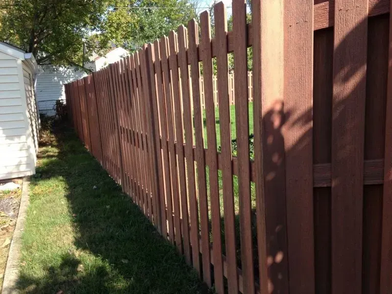 A composite fence with a white house in the background in Grove City