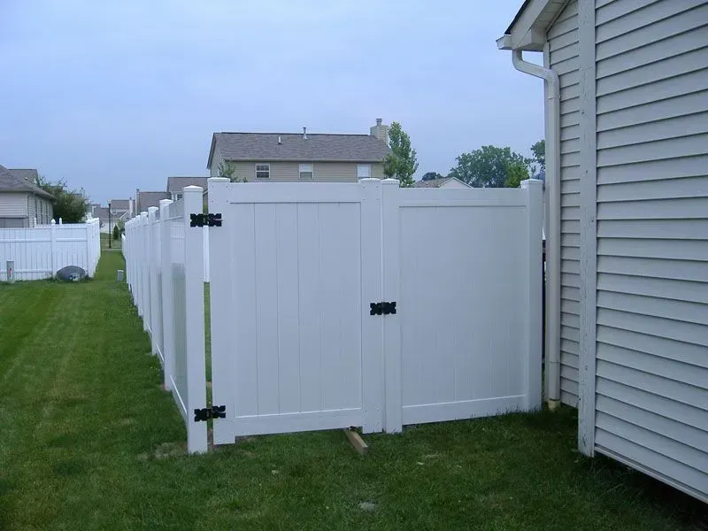 A white vinyl fence with a gate in the backyard of a house in Columbus