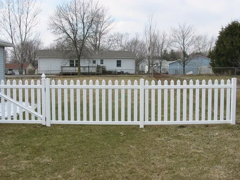 A white picket vinyl fence with a gate in front of a house in Columbus