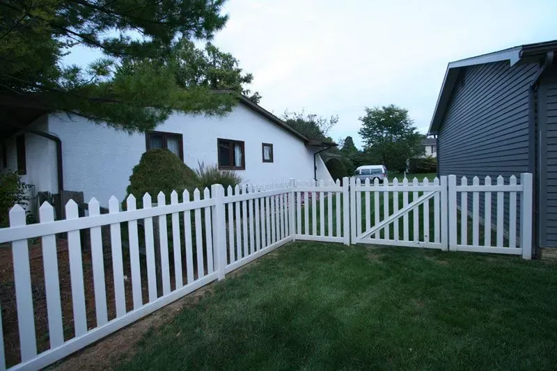 A white picket vinyl fence is in the backyard of a house in Columbus