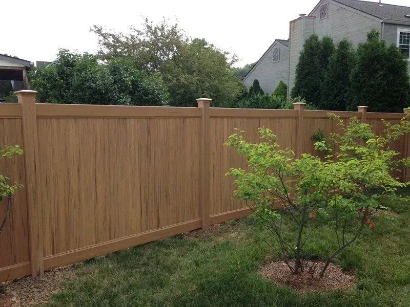 A vinyl fence surrounds a small tree in a backyard in Columbus