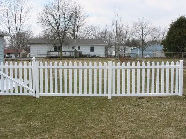 A white vinyl picket fence surrounds a grassy yard in front of a house in Columbus