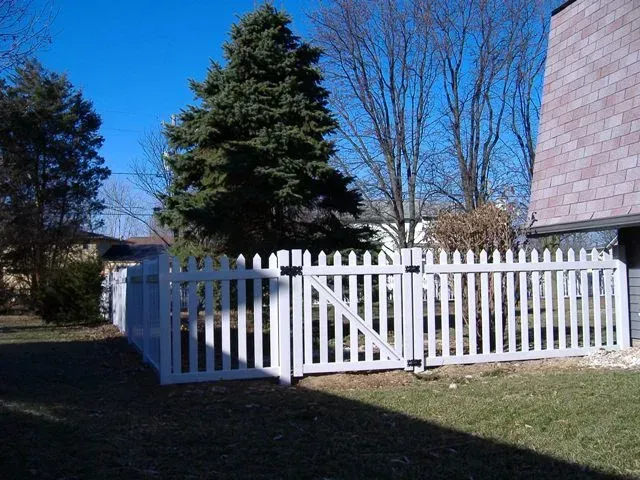 A white vinyl picket fence is in front of a house in Columbus