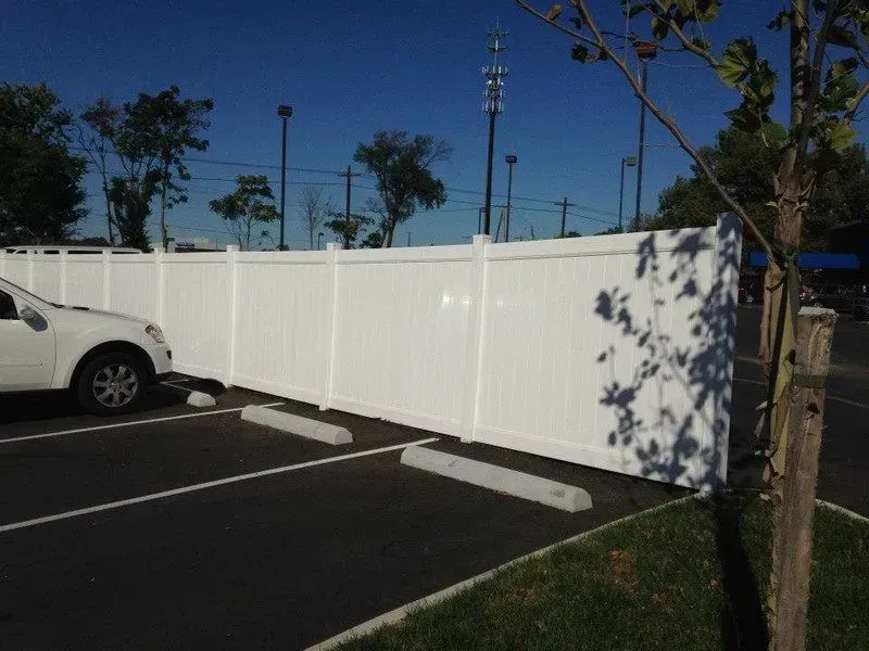 A white car is parked in front of a white vinyl fence in Columbus