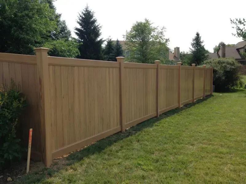 A vinyl fence surrounds a lush green lawn in a backyard in Columbus