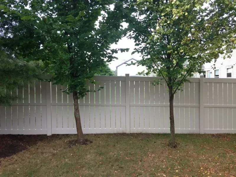 A vinyl white fence with trees in front of it in Columbus
