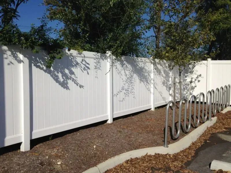A vinyl white fence with a row of bike racks in front of it in Columbus