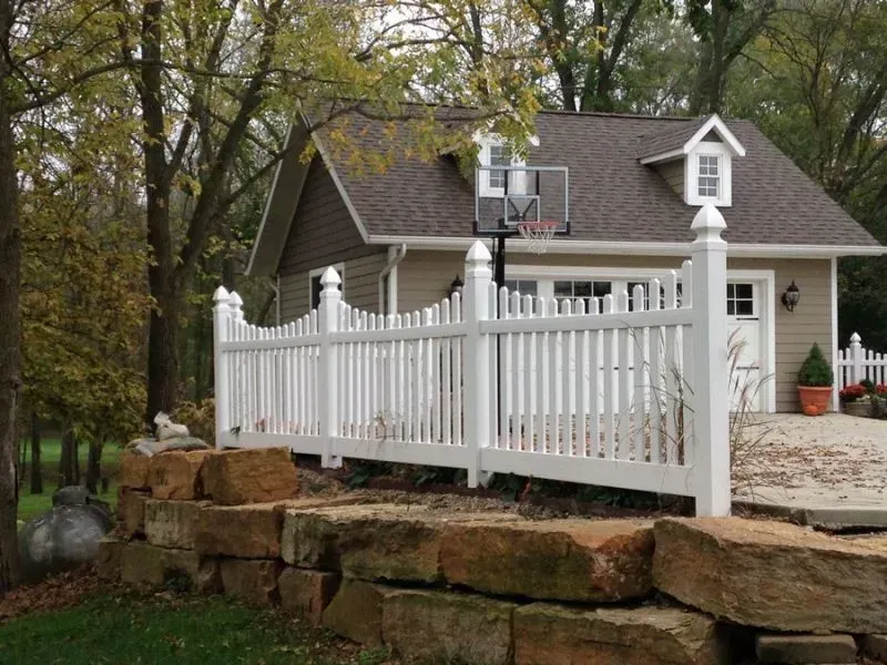 A house with a white picket vinyl fence and a basketball hoop in front of it in Columbus