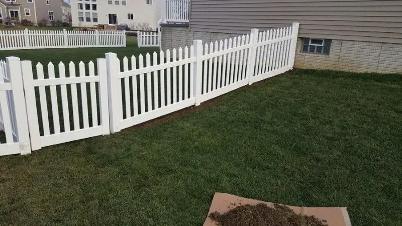 A white picket vinyl fence surrounds a lush green lawn in a backyard in Columbus