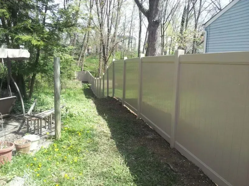 A tan vinyl fence surrounds a lush green yard in Columbus